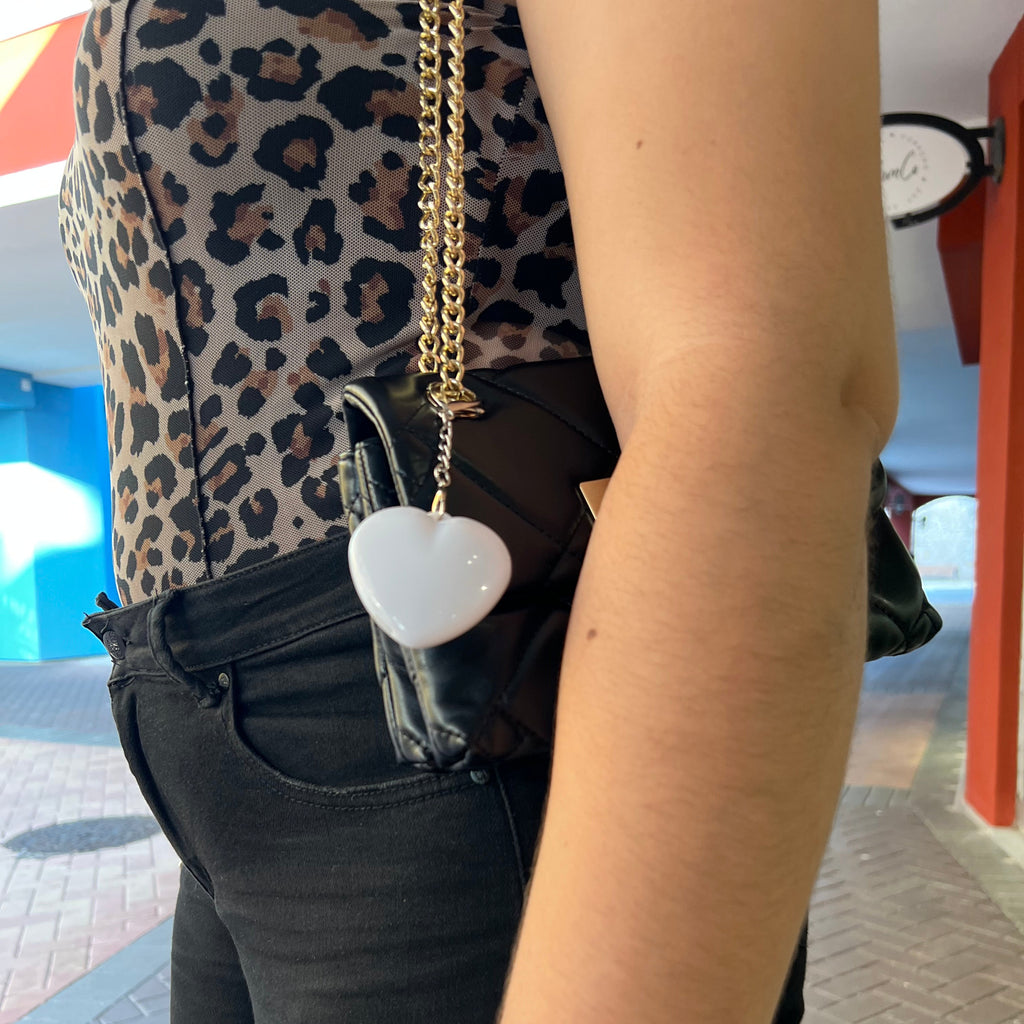 Person wearing a leopard print jacket with a black bag and gold chain.