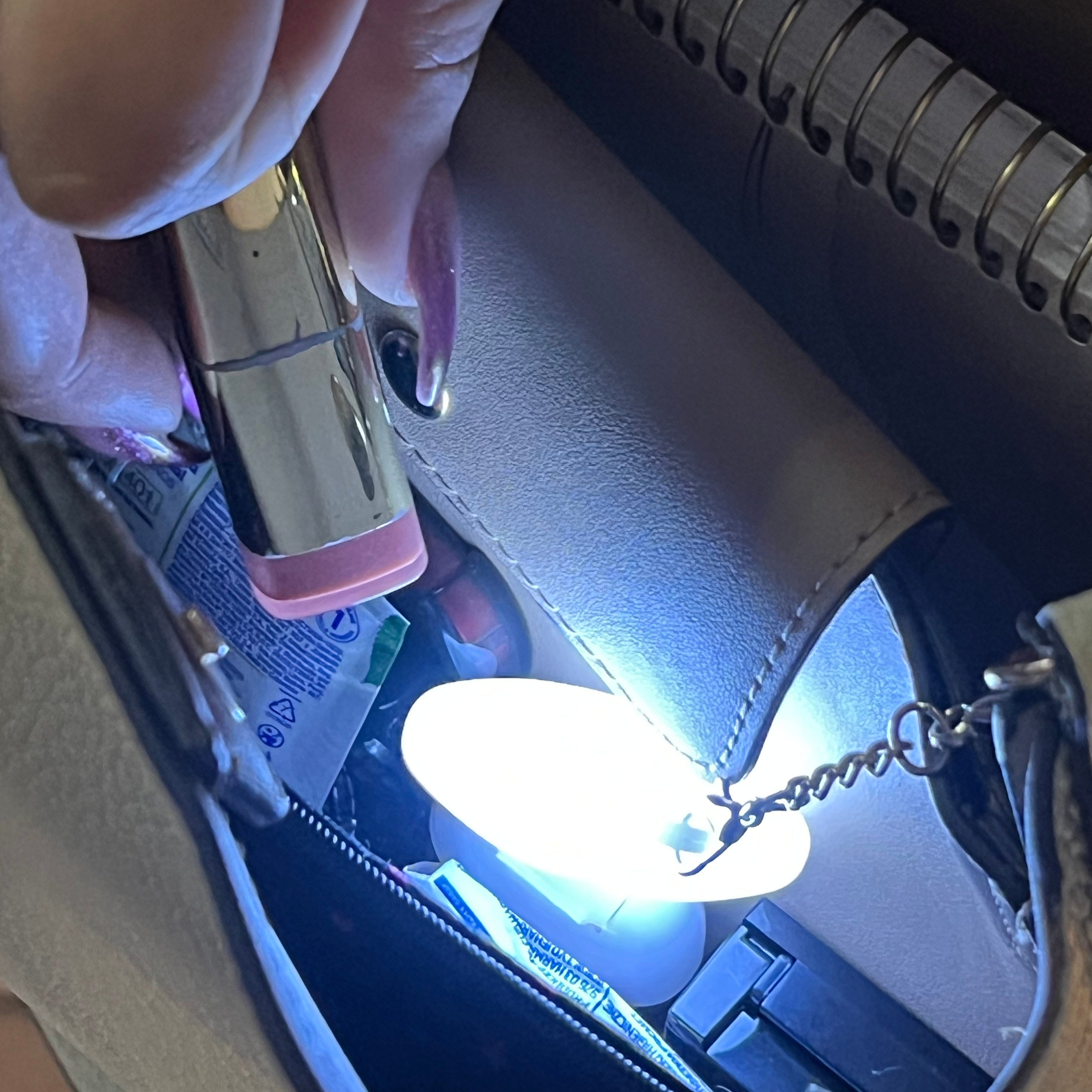 Person holding a lipstick with a light shining on it inside a bag.